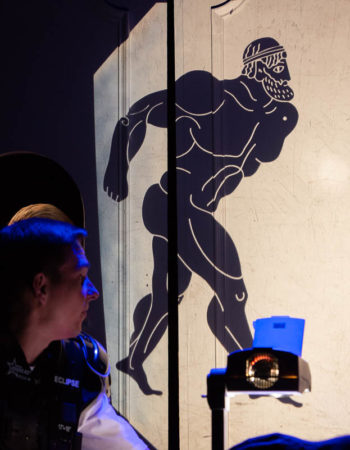 Chłopiec przygląda się wyświetlonej z projektora na ścianie sylwetce Heraklesa.