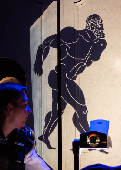 Chłopiec przygląda się wyświetlonej z projektora na ścianie sylwetce Heraklesa.
