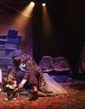 Aktorzy na tle dekoracji trzymają lalki misia i tygryska