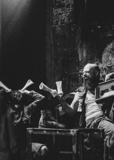 aktor smutny stoi z boku inni aktorzy wyśmiewają go siedząc obok na scenie