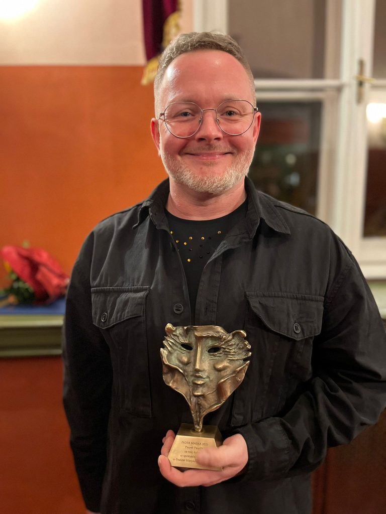 Uśmiechnięty mężczyzna z nagrodą w ręce.